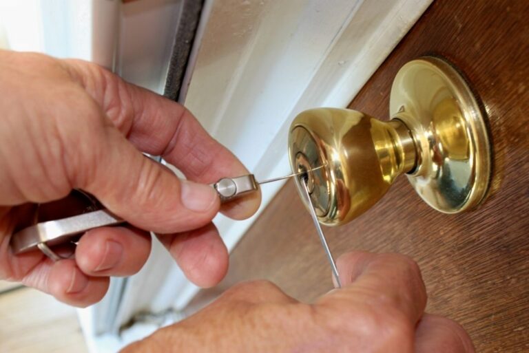 A person uses lockpicking tools to open a gold-colored door lock.