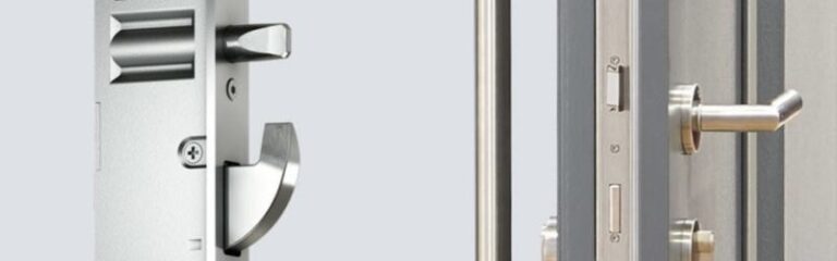 Close-up of a modern metal door lock mechanism and handle on a partially open door, showing security hardware details.