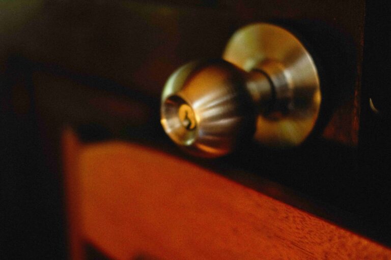Close-up of a metallic doorknob attached to a wooden door, with warm lighting highlighting the textures—a scene often encountered by an Emergency Locksmith Vancouver during urgent service calls.