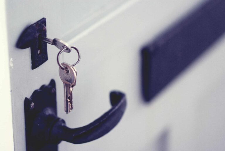 Close-up of a door handle with a set of keys inserted into the keyhole of a white door, illustrating the kind of situation where an emergency residential locksmith in Vancouver may be needed.